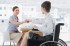 Businesswoman shaking hands with disabled colleague at desk in o