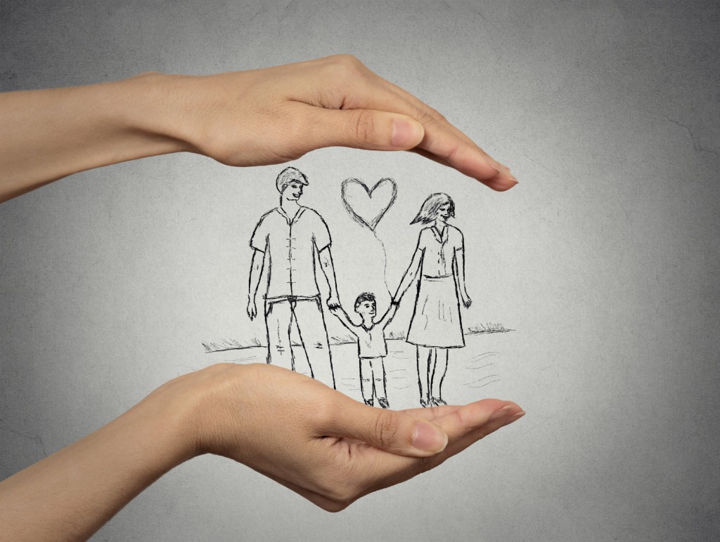 woman's hands protecting happy family