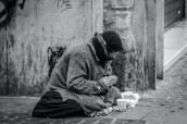 grayscale-photography-of-man-praying-on-sidewalk-with-food-1058068