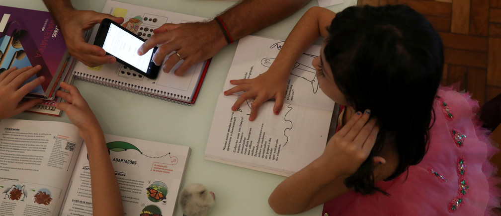 Еліс, 5 років, переглядає відео, надіслане зі школи, в ході навчання вдома з батьком під час карантину в Санто-Андре, Бразилія. Зображення: REUTERS/Amanda Perobelli