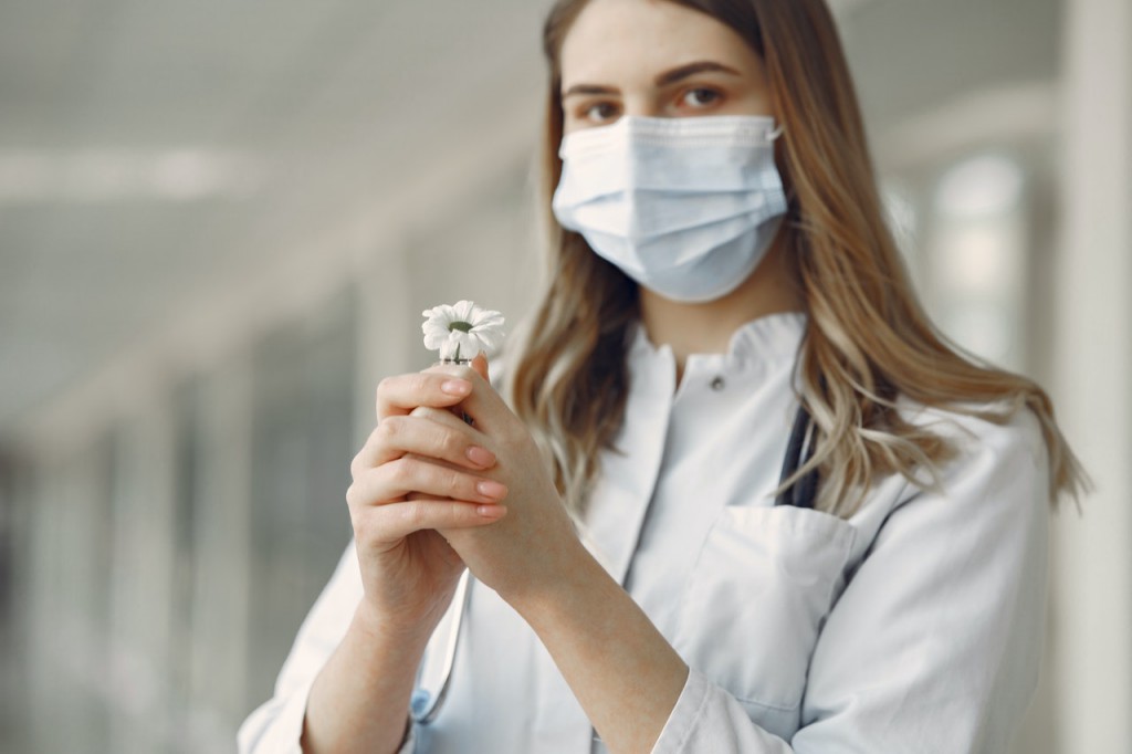 woman-in-white-button-up-shirt-with-white-face-mask-holding-3985156