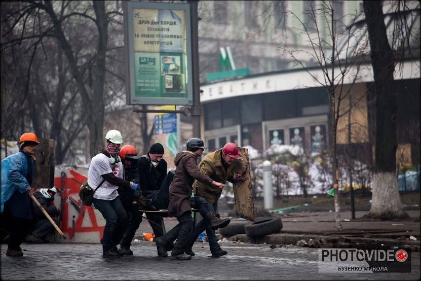 Побратими виносять пораненого Василя з Інститутської. У білій футболці і шоломі - медик-волонтер Іван Жолобан, який надав першу допомогу пораненому. Фото: Микола Бузенко.