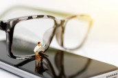 Miniature people reading newpapers with glasses, education or business concept.