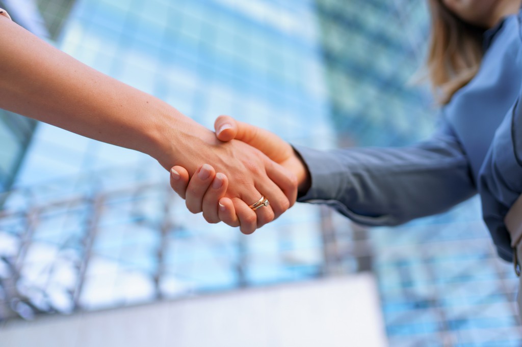 Woman hands shake on business building background