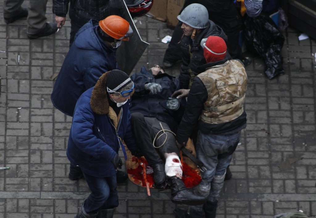 Anti-government protesters carry an injured man on a stretcher in Independence Square in Kiev