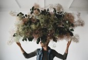 Large decorative bouquet made of green leaves and moss hangs ove