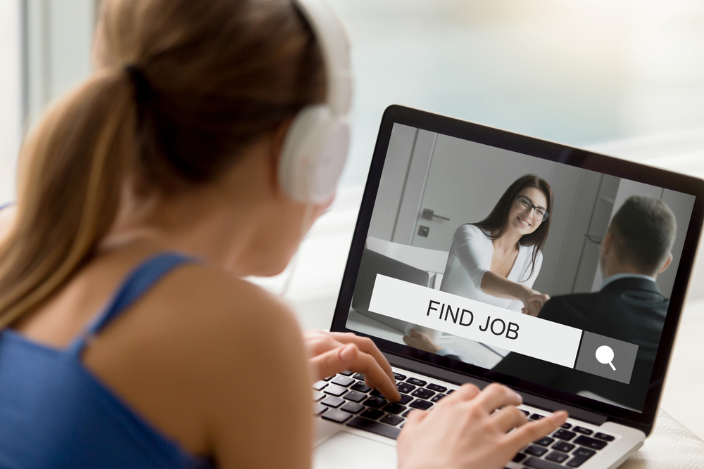 Woman in headphones looking trying to find job online.