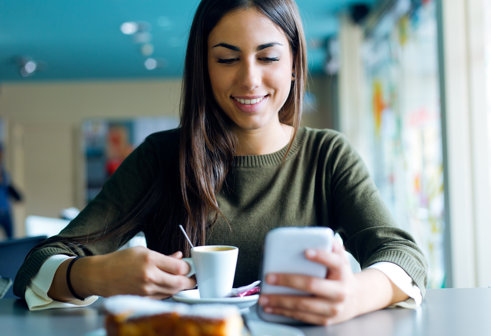 Beautiful girl using her mobile phone in cafe.