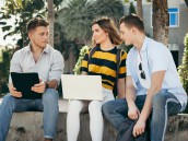 Happy university student using laptop together outside building