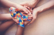 Hands holding puzzle ribbon for autism awareness