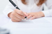 Business women filling contract at desk.