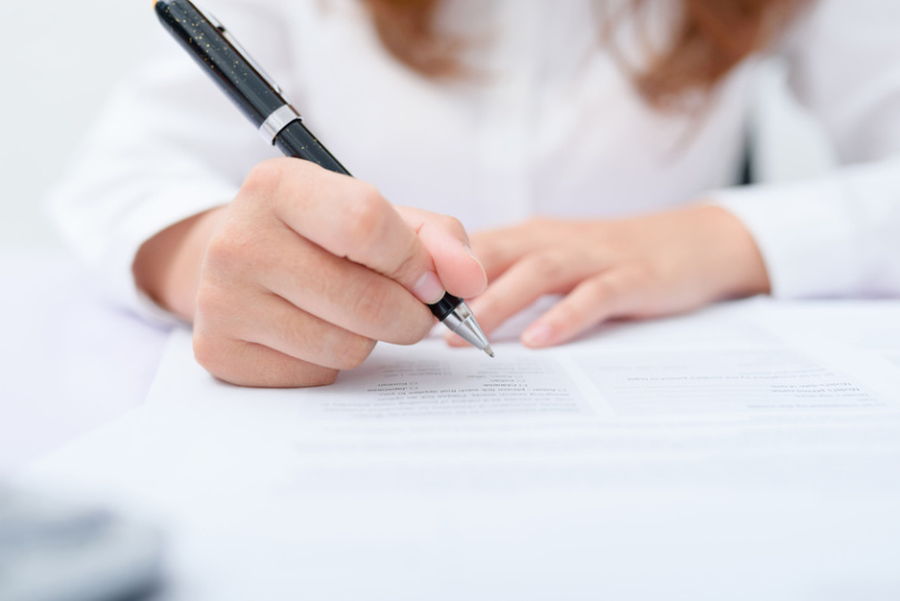 Business women filling contract at desk.