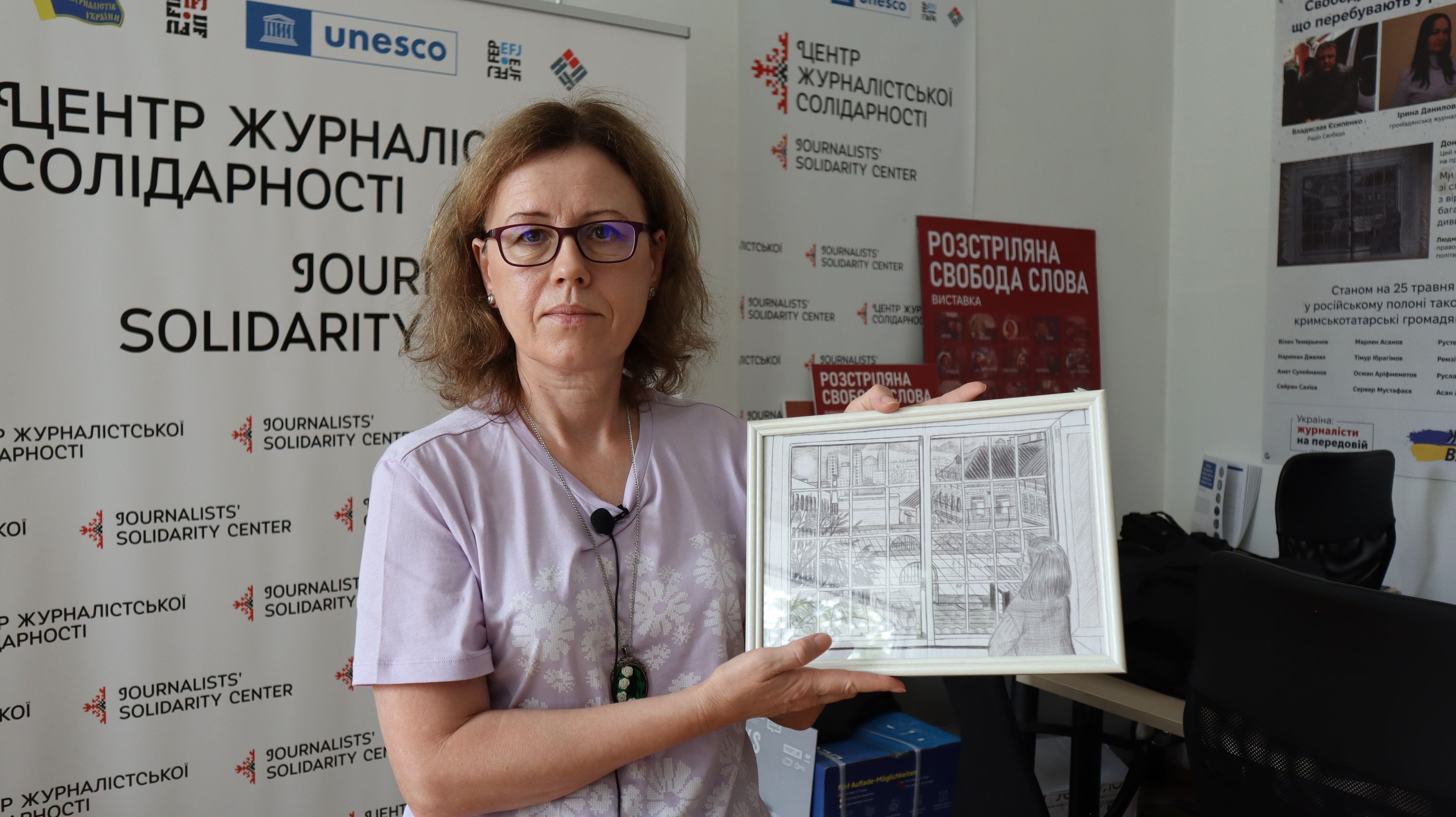 Ліна Кущ показує малюнок, який Людмила Гусейнова змогла забрати з собою із Донецького СІЗО, де вона провела три роки. Малюнок створений її співкамерницею на шматку простирадла. Саме так жінка побачила Людмилу, яка стоїть і дивиться крізь заґратоване вікно на вільне життя.