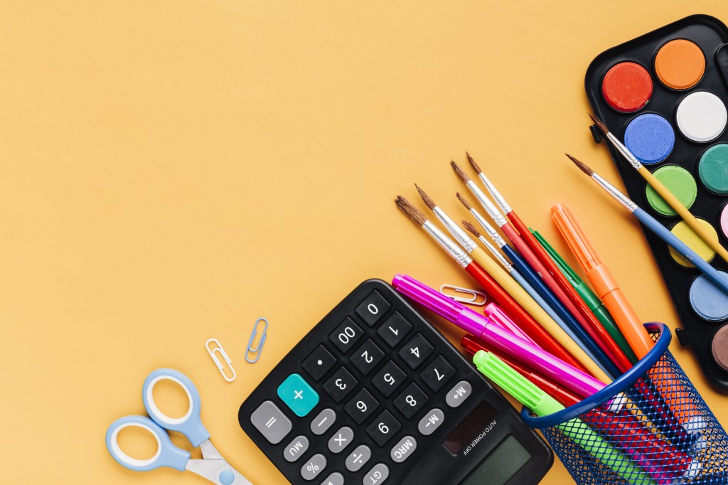 calculator-with-scissors-drawing-tools-scattered-yellow-desk