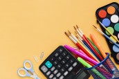 calculator-with-scissors-drawing-tools-scattered-yellow-desk